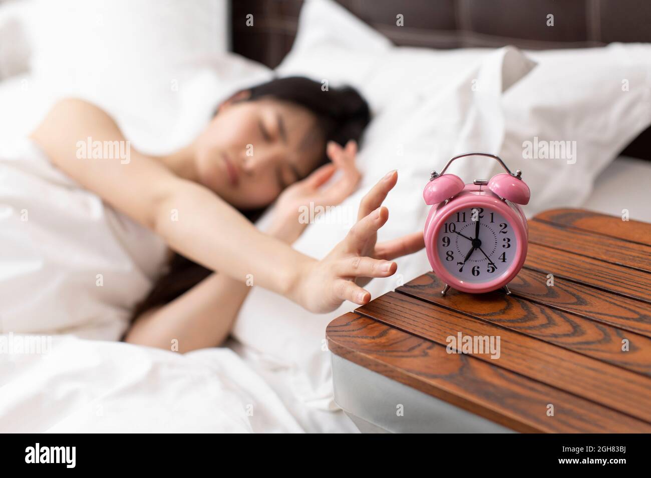 Junge Frau, die den Wecker abschaltet Stockfoto