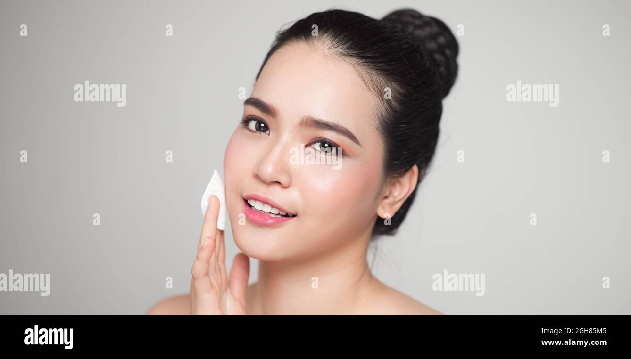 Glücklich lächelnde schöne Asiatin mit Wattepad Reinigung der Haut. Stockfoto