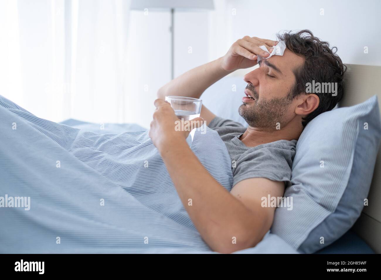 Ein Mann, der von Erkältung und Grippe betroffen ist, liegt im Bett  Stockfotografie - Alamy