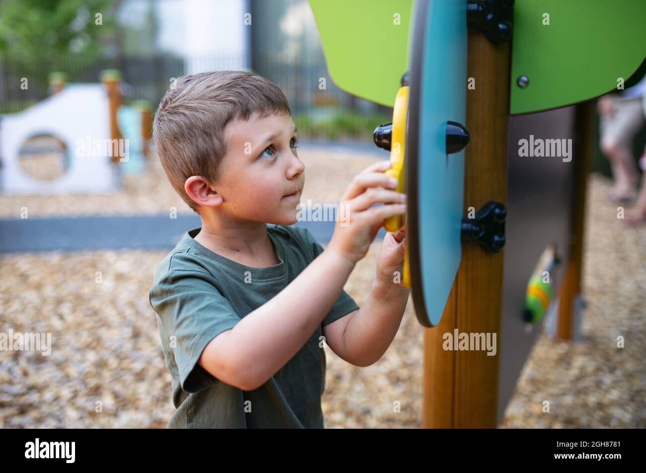 Kleiner fröhlicher Kindergartenjunge, der draußen auf dem Spielplatz spielt. Stockfoto
