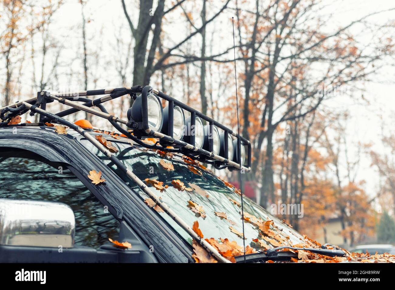 Nahaufnahme der individuell angefertigten Dachgepäckträger mit zusätzlichem Scheinwerfer, der auf dem Dach eines Hochleistungs-suv-Pick-up gegen den nebligen Herbstwald montiert ist Stockfoto