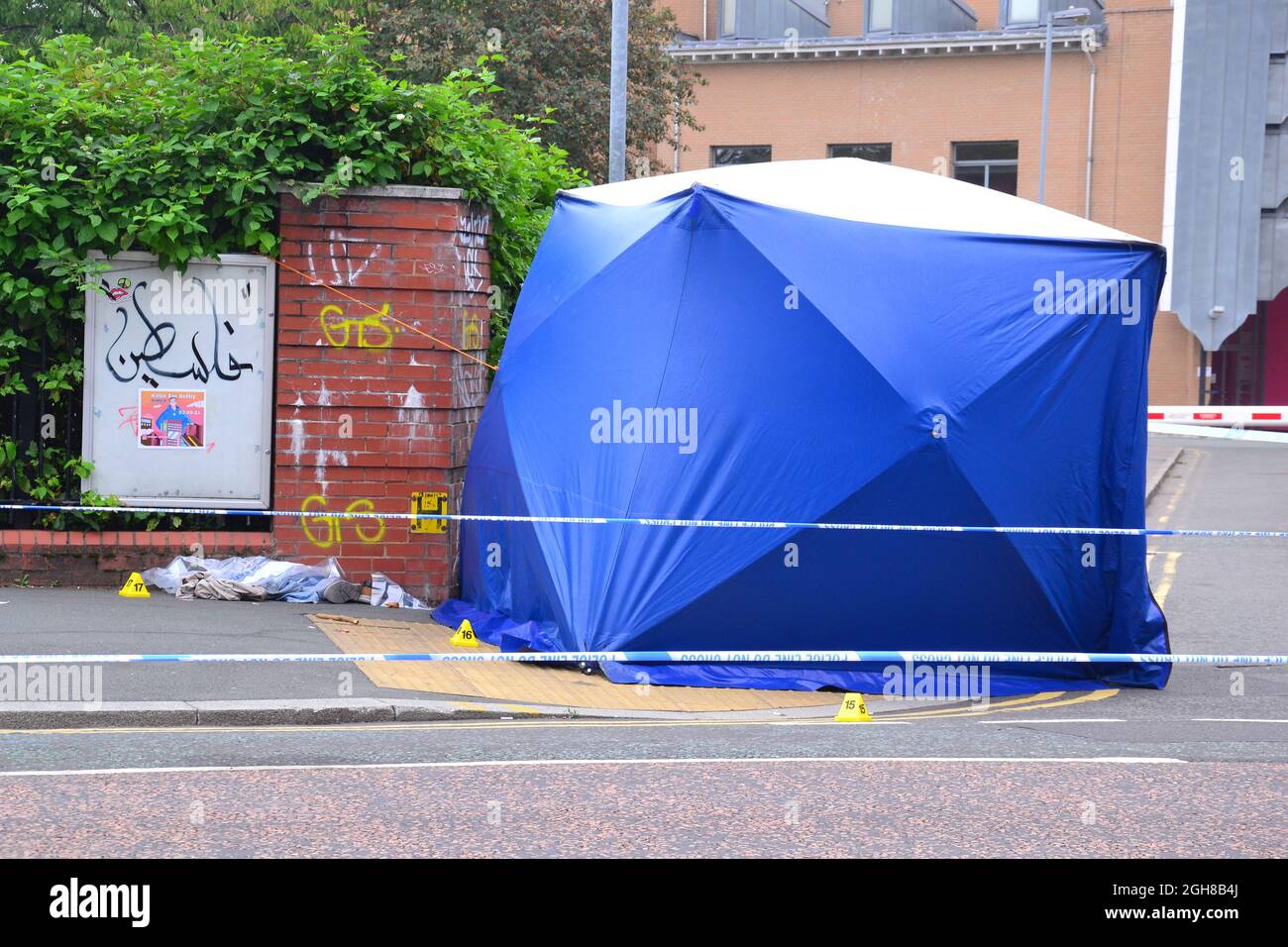 Manchester, Großbritannien, 6. September 2021. Die Polizei sperrte die Kreuzung von Oxford Road und Devas Street ab und forensische Beamte untersuchen um ein Polizeizelt herum, wobei uniformierte Beamte den Tatort bewachen. Evidenzmarker sind auf dem Boden. Die Polizei von Greater Manchester sagte: „dieser Vorfall hat dazu geführt, dass ein Mann schwere Kopfverletzungen erlitten hat.“ Detritus und Beweismarkierungen auf dem Boden neben einem Polizeizelt. Quelle: Terry Waller/Alamy Live News Stockfoto