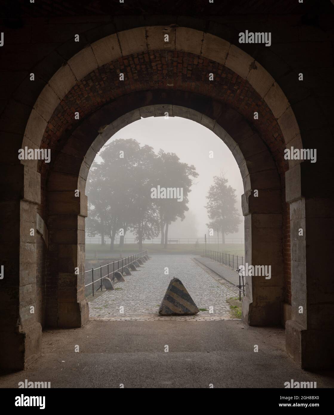 Blick durch das Obere Wassertor (Horní vodní brána) in der böhmischen Stadt Terezín auf die Brücke über den Burggraben. Nebliger Morgen. Stockfoto