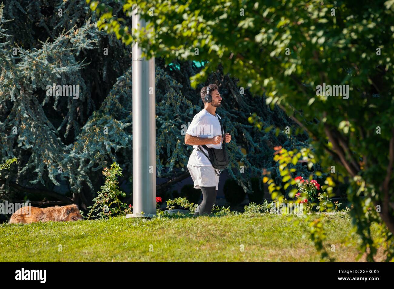 Ankara, Türkei - 02. September 2021: Junger Mann, der an einem sonnigen Morgen im Park läuft, während er in Dikmen mit kabellosen Kopfhörern Musik hört Stockfoto