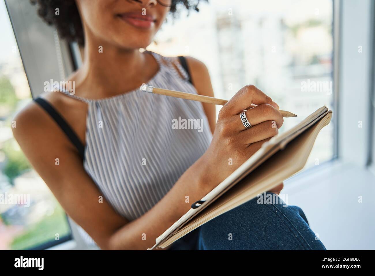 Frau saß am Fenster und machte sich Notizen in ihrem Tagebuch Stockfoto