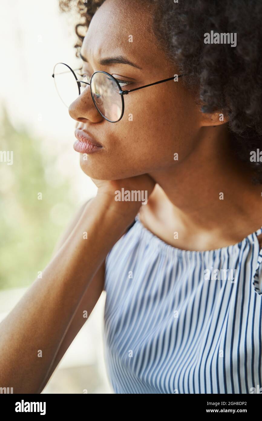 Leises Weibchen in trendigen Kreisbrillen, das in die Ferne starrt Stockfoto