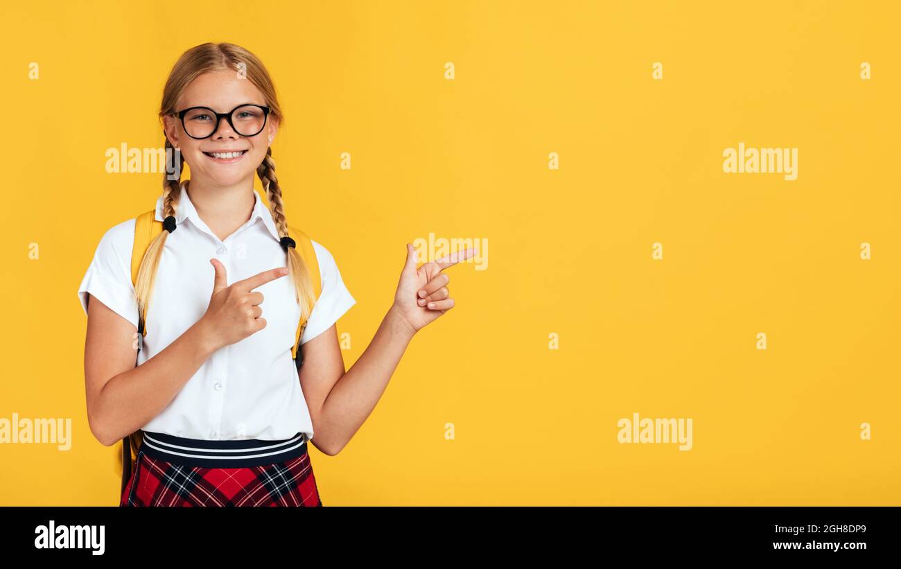 Lächelnd niedlich smart pubertär blonde Hämale Pupille in Brille zeigt Finger zu leeren Raum Stockfoto