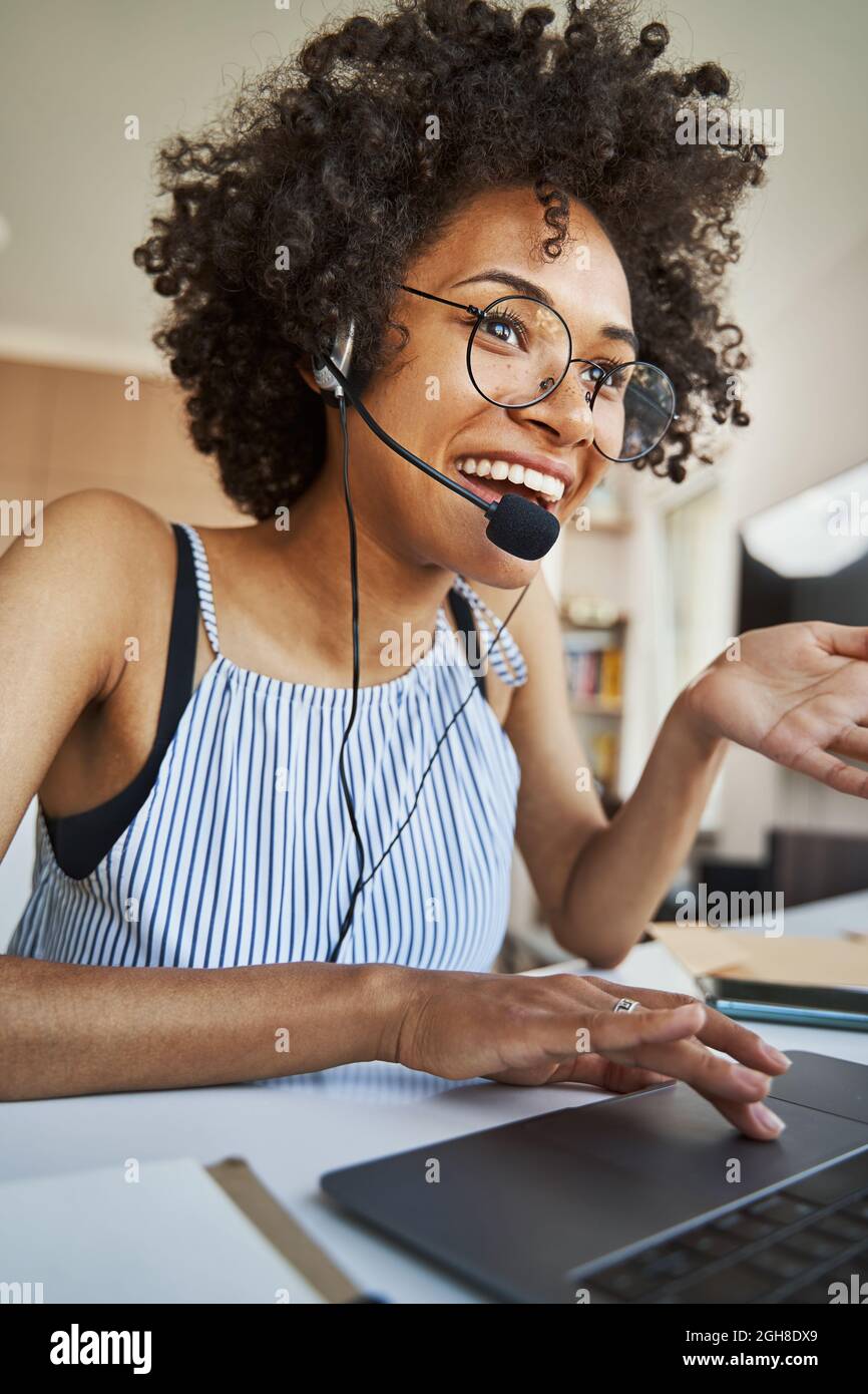 Fröhliche Freiberuflerin im Headset, die online kommuniziert Stockfoto