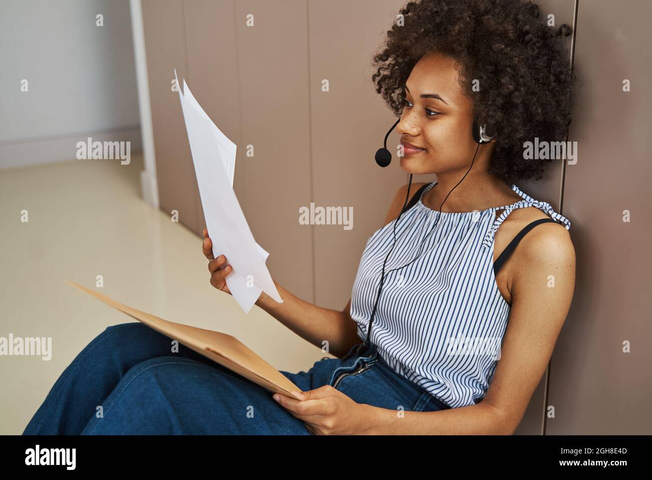 Fokussierte, ruhige Frau im Headset, die die Dokumentation analysiert Stockfoto