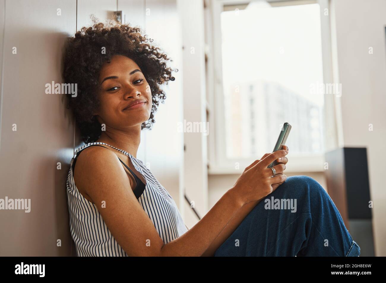 Erfreut afroamerikanische Frau mit ihrem Smartphone nach vorne schauen Stockfoto