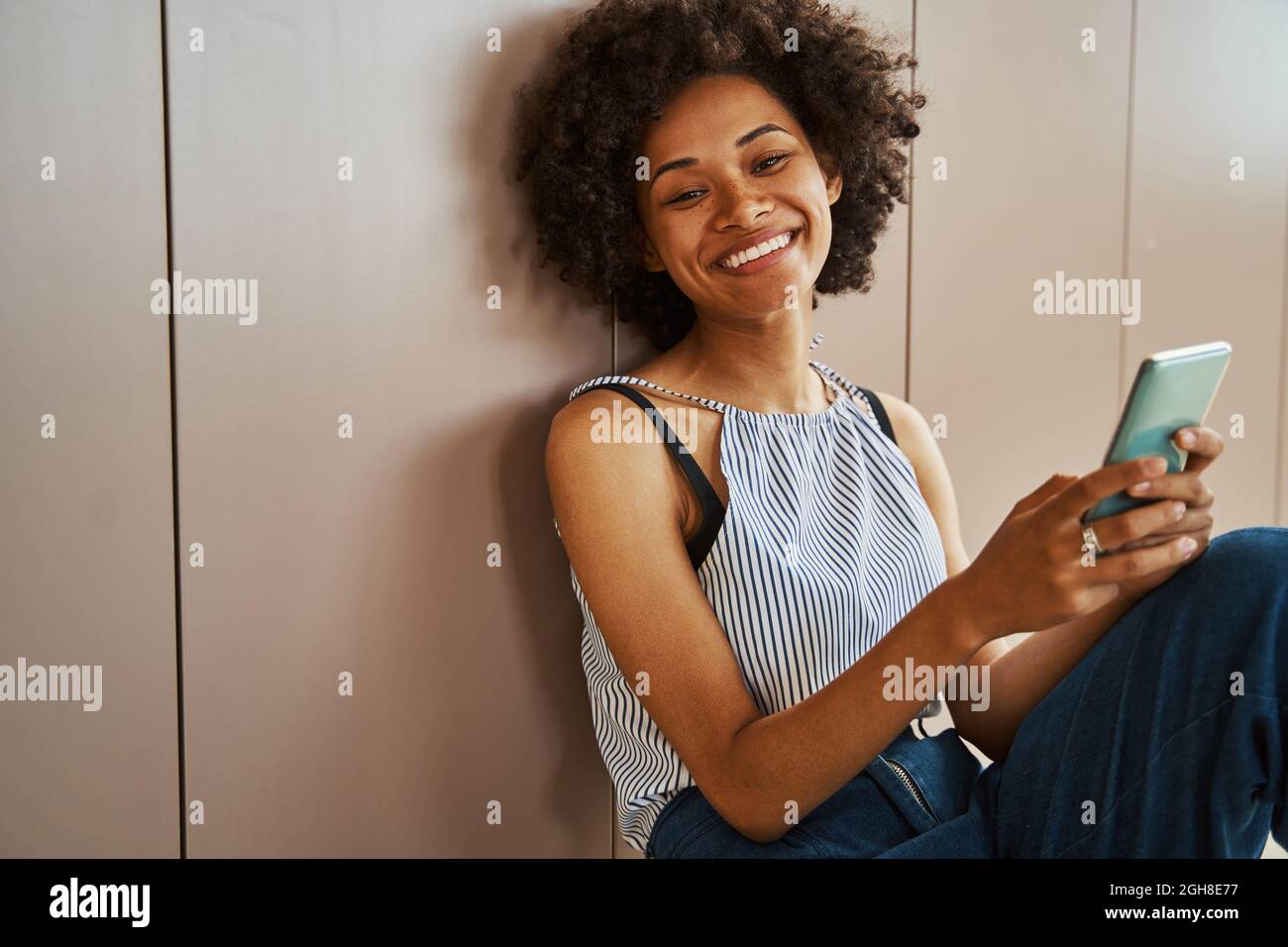 Die Dame mit einem Handy lehnte sich gegen ein Möbelstück Stockfoto