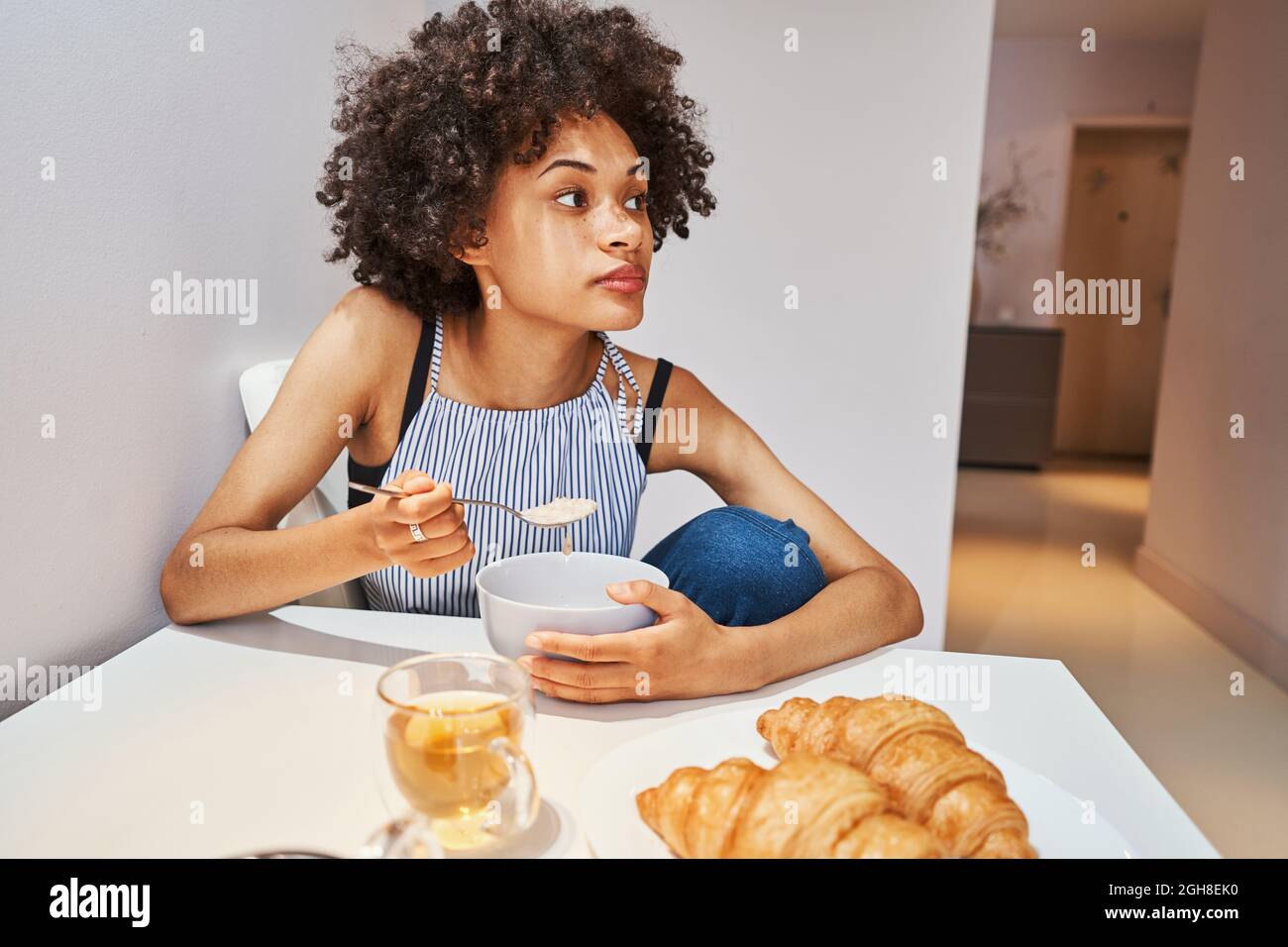 Frau, die während des Essens am Küchentisch sitzt Stockfoto