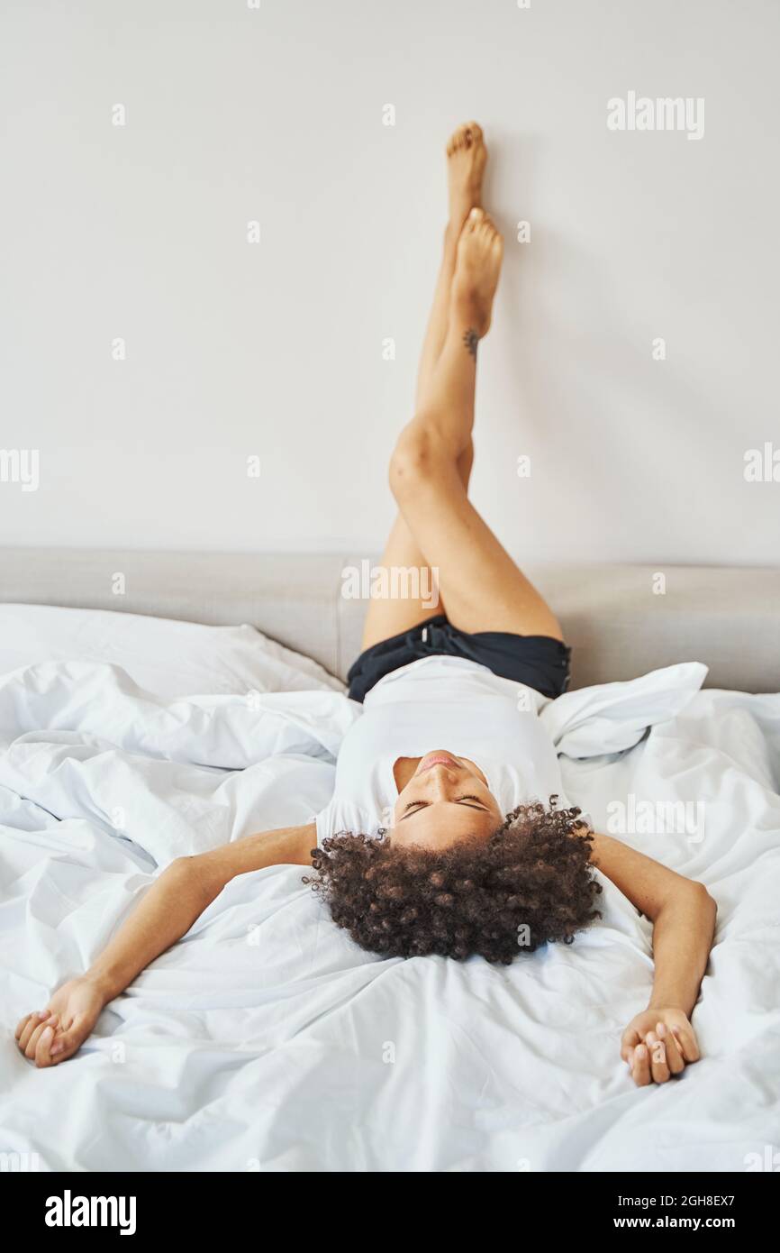 Frau mit dicken dunklen lockigen Haaren, die in ihrem Schlafzimmer ruht Stockfoto