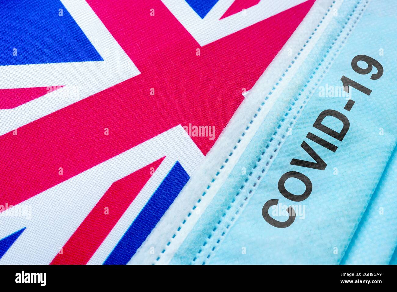 Britische Flagge und Gesichtsmaske mit covid-19 Wörtern. Stockfoto