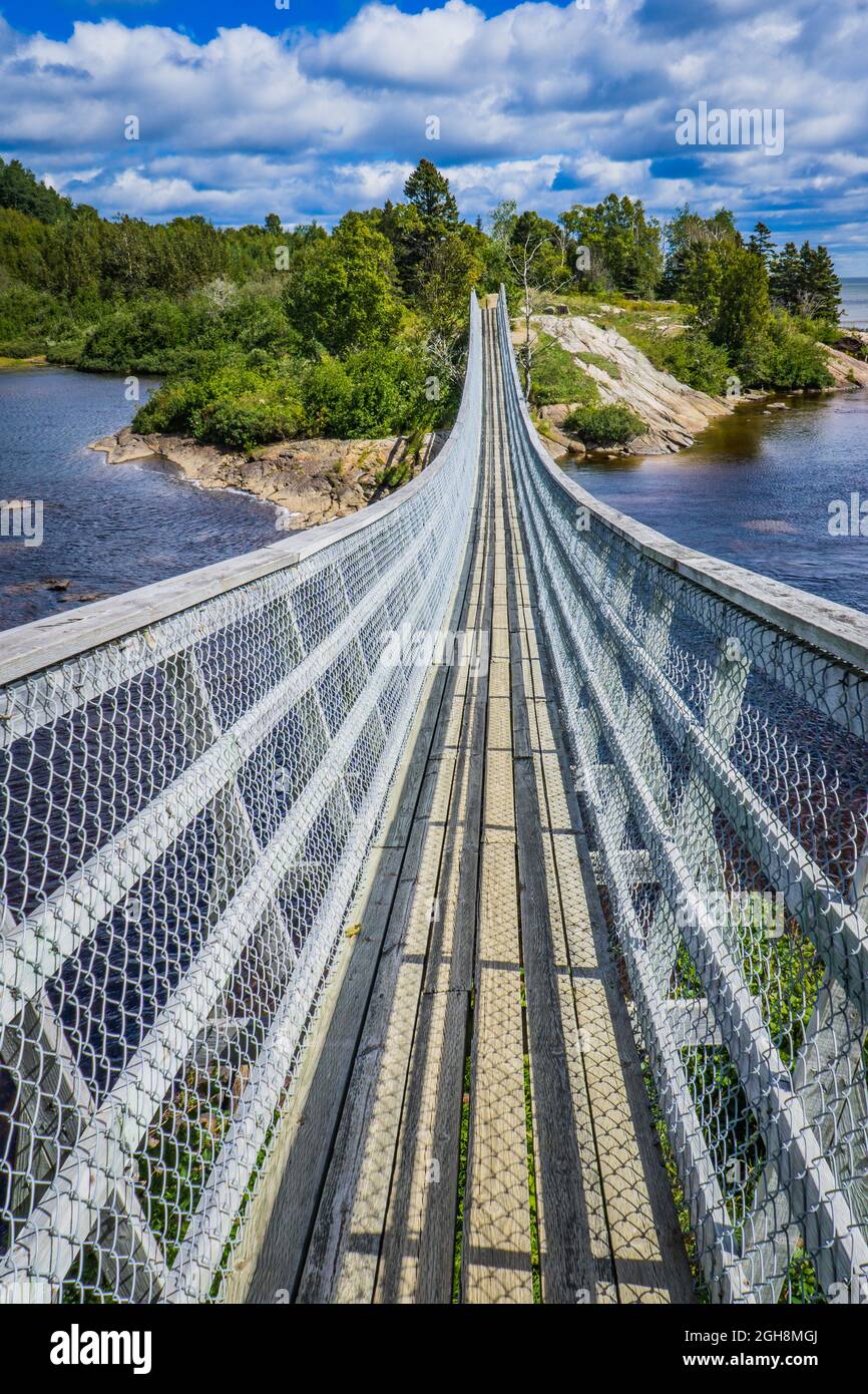 Fußgängerbrücke über den Sault Au Mouton Wasserfall in Cote Nord, Quebec (Kanada), mit dem St. Lawrence Fluss auf der rechten Seite Stockfoto