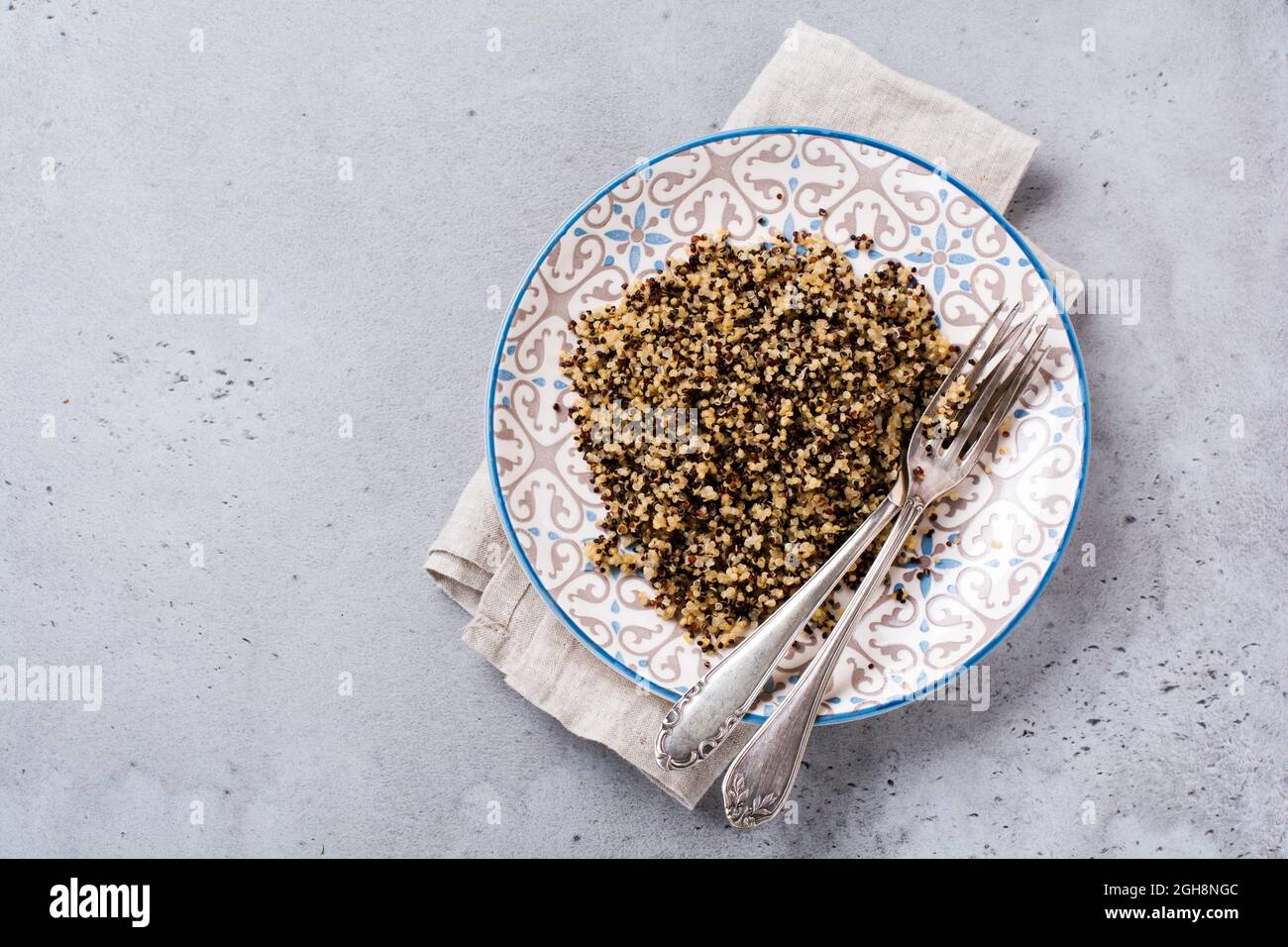 Gekochte weiße, rote und schwarze Quinoa in weißer Platte auf grauem rustikalem Hintergrund, Draufsicht, Platz für Textrezepte oder Menü. Vegan Superfood, gesunde Ernährung Stockfoto