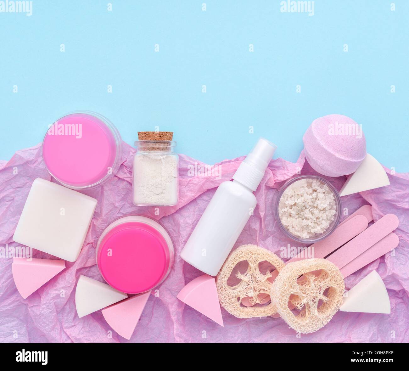 Hautpflegeprodukt - Cremes, Lotion, Seife, Schwämme, Badesalz auf rosa und blauem Hintergrund. Flachbild mit Kopierplatz. Stockfoto