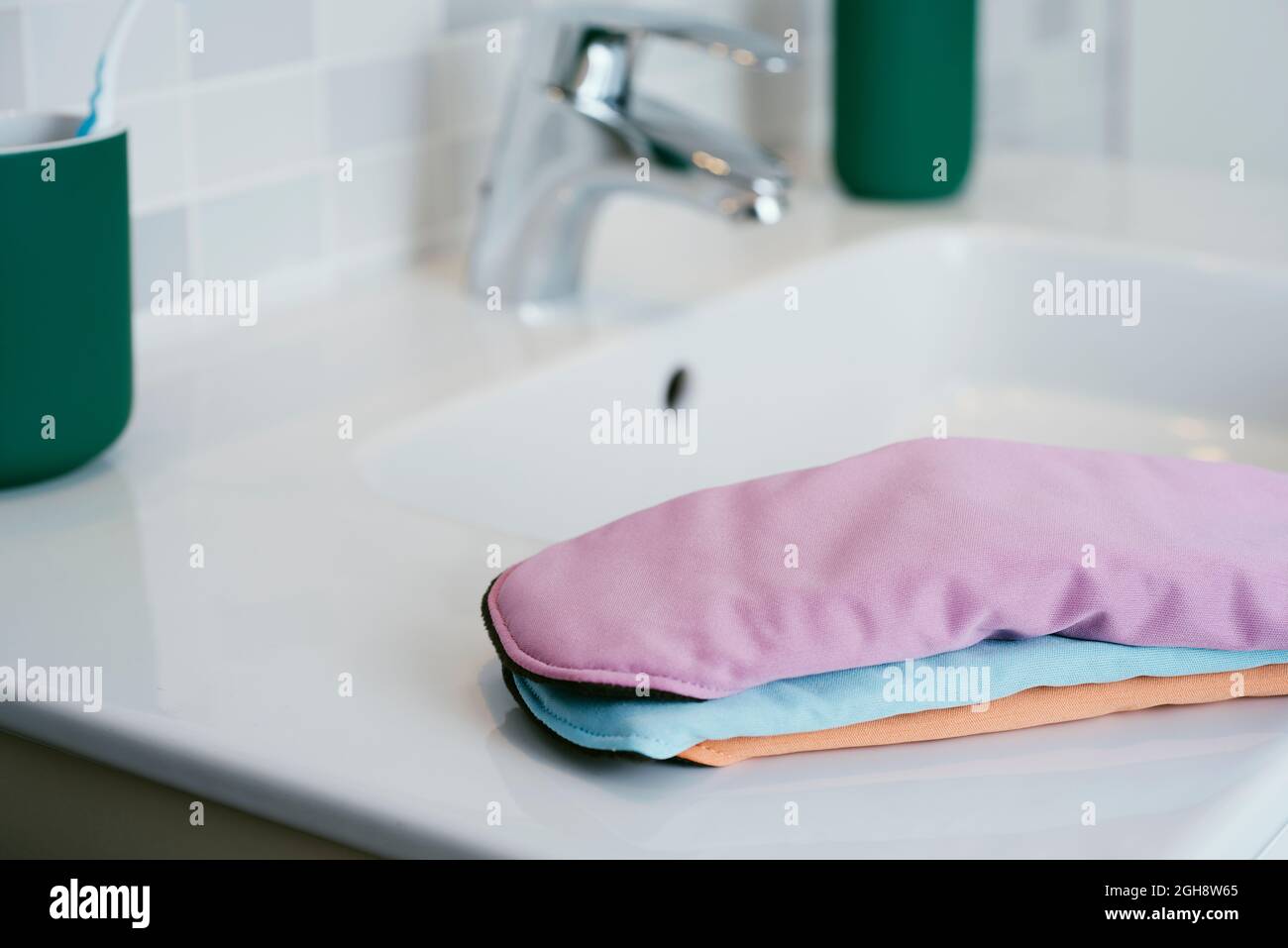 Einige Stoff Menstruationskissen in verschiedenen Farben auf dem weißen Porzellanwaschbecken eines modernen Badezimmers Stockfoto