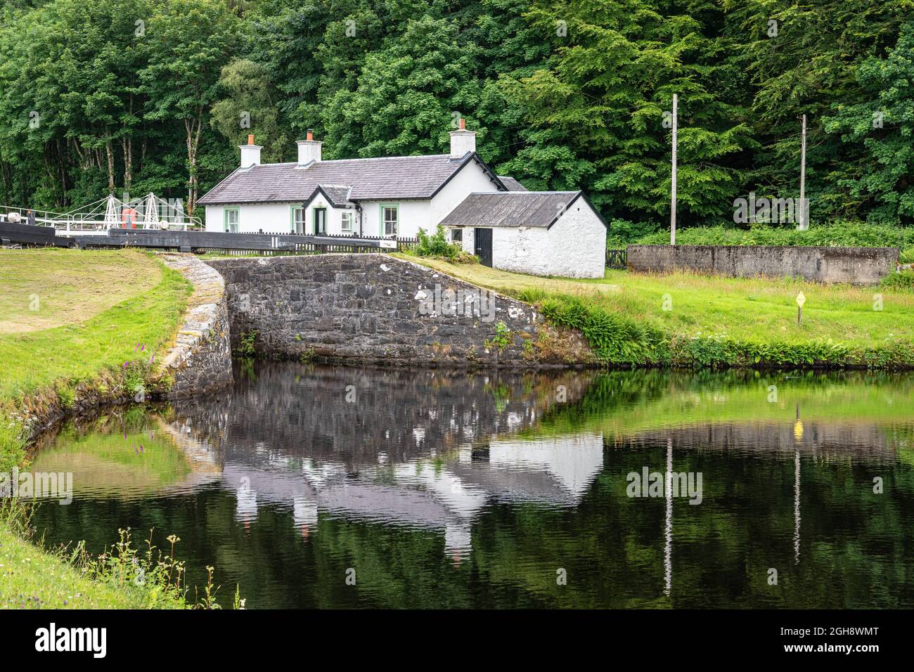 Lock Keepers Cottage spiegelt sich im Pool unter Lock 11, Argyll and Bute, Schottland, wider Stockfoto