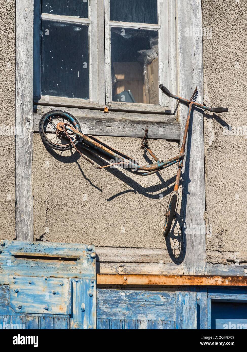 Alte rostige Motorroller oder Fahrrad an der Wand eines Antiquitätenläden in Bourganeuf, Creuse (23), Nouvelle-Aquitaine, Frankreich montiert. Stockfoto