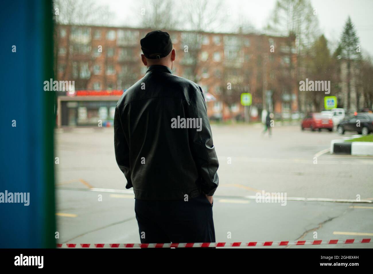 Ein Mann in einer schwarzen Jacke wartet auf die Straße. Unbekannter Typ. Warten auf ein Meeting. Die russische Realität des einfachen Mannes auf der Straße. Stockfoto