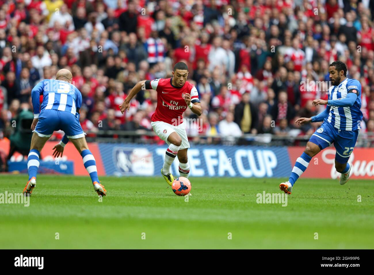 Alex Oxlade-Chamberlain von Arsenal läuft am 12. April 2014 im Halbfinale des FA Cup zwischen Arsenal und Wigan Athletic im Wembley Stadium in London, England, gegen Stephen Crainey von Wigan und James Perch von Wigan. Pic Charlie Forgham-Bailey Stockfoto