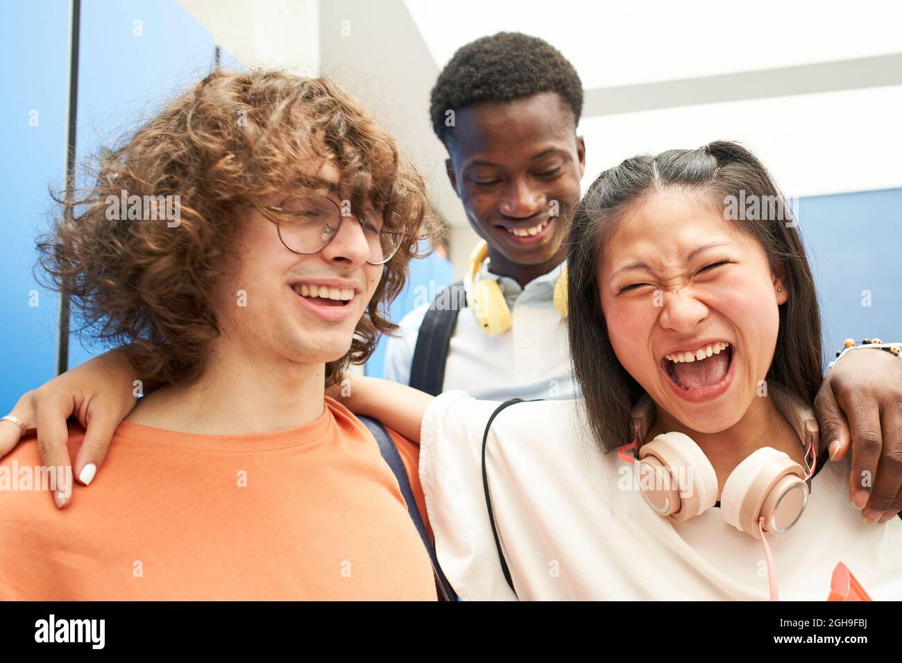 Porträt von drei multirassischen Studenten, die die Kamera mit einem Lächeln auf eine High School anschauten. Stockfoto