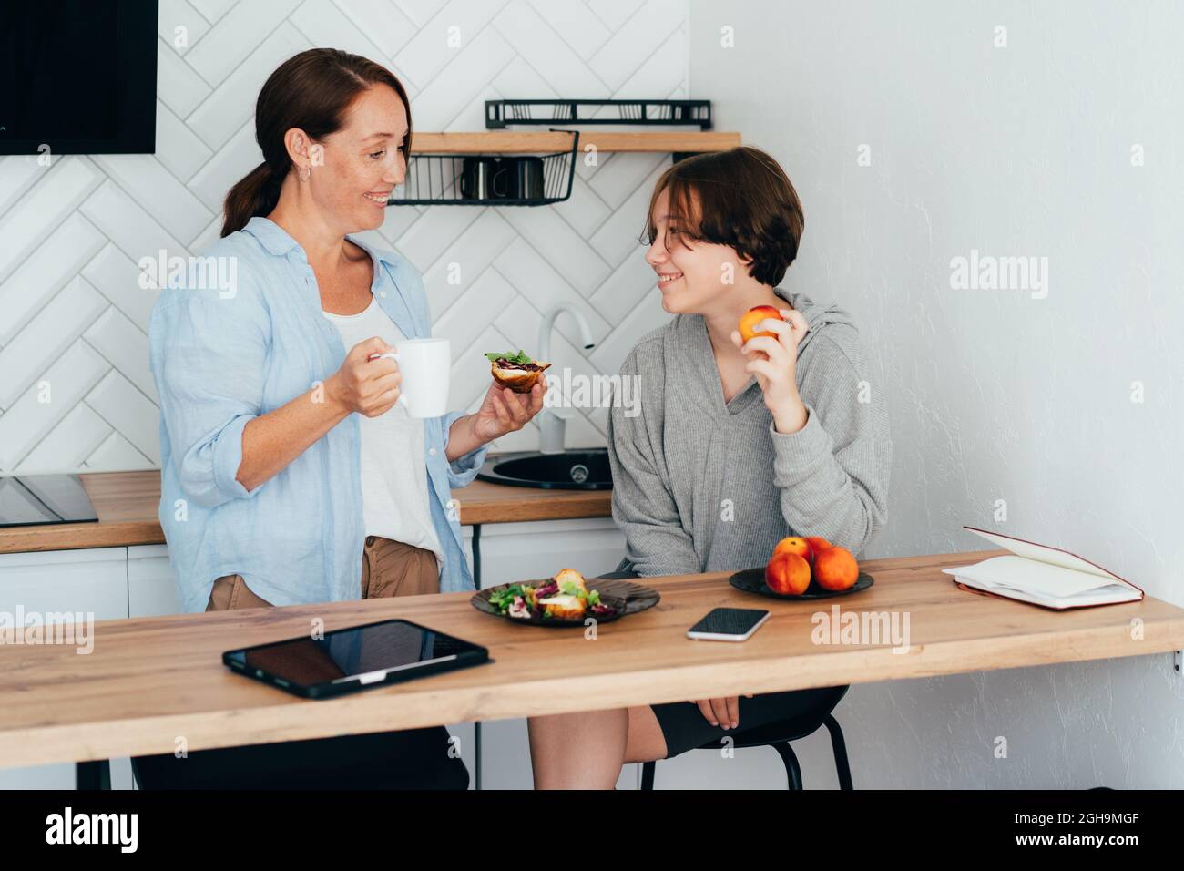 Beziehung zwischen einem Teenager und einem Elternteil. Mutter und Tochter im Teenageralter frühstücken Stockfoto