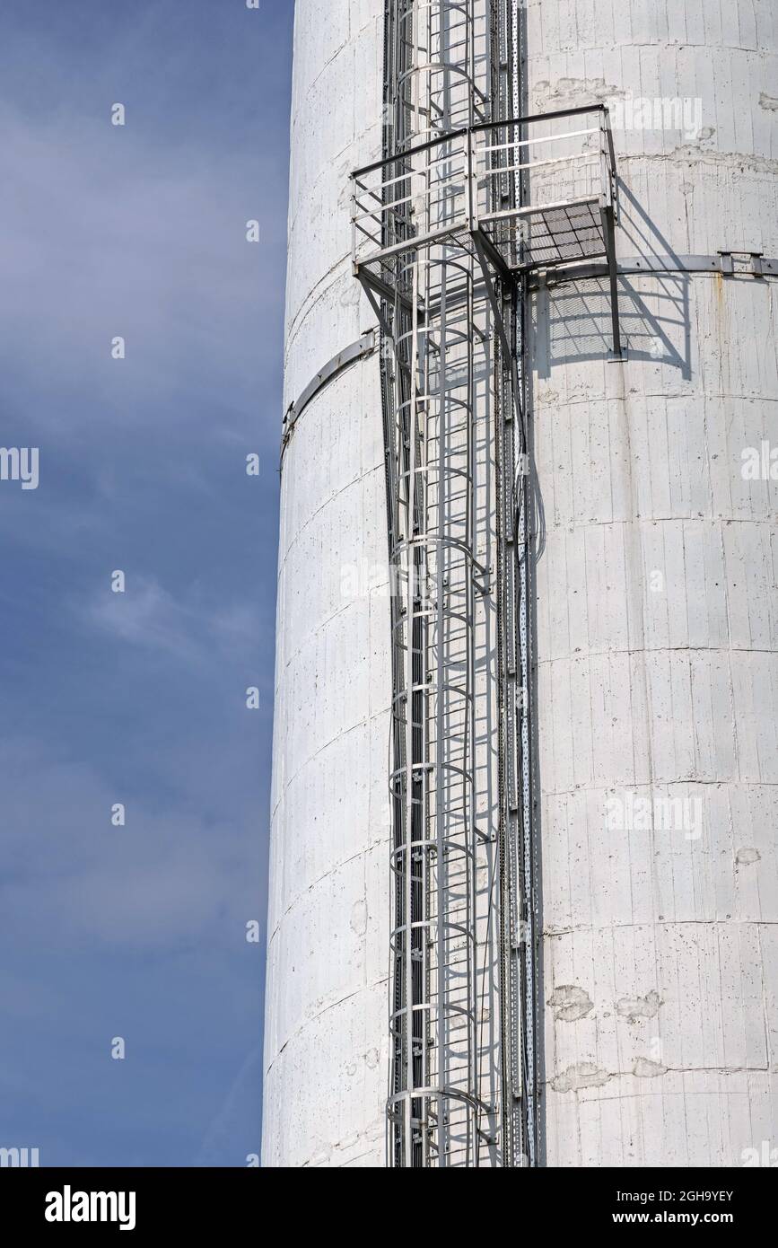 Stahlleiter mit Sicherheitskäfig bei hoher Kaminstruktur Stockfoto