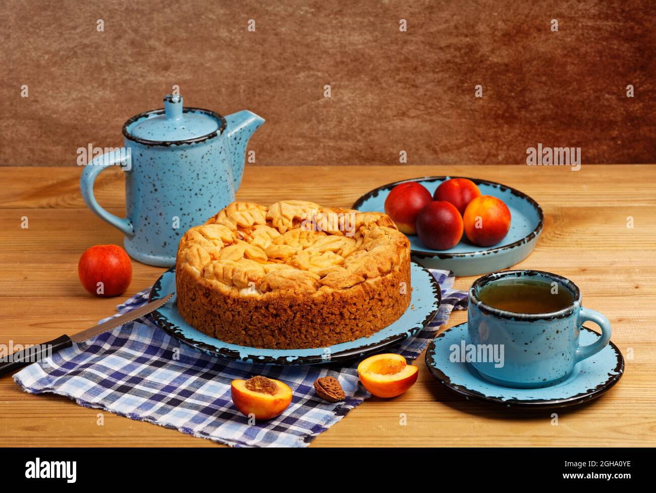 Hausgemachter Kuchen mit Nektarinen und einer Tasse Tee auf einem Holztisch. Geringer Fokus. Stockfoto