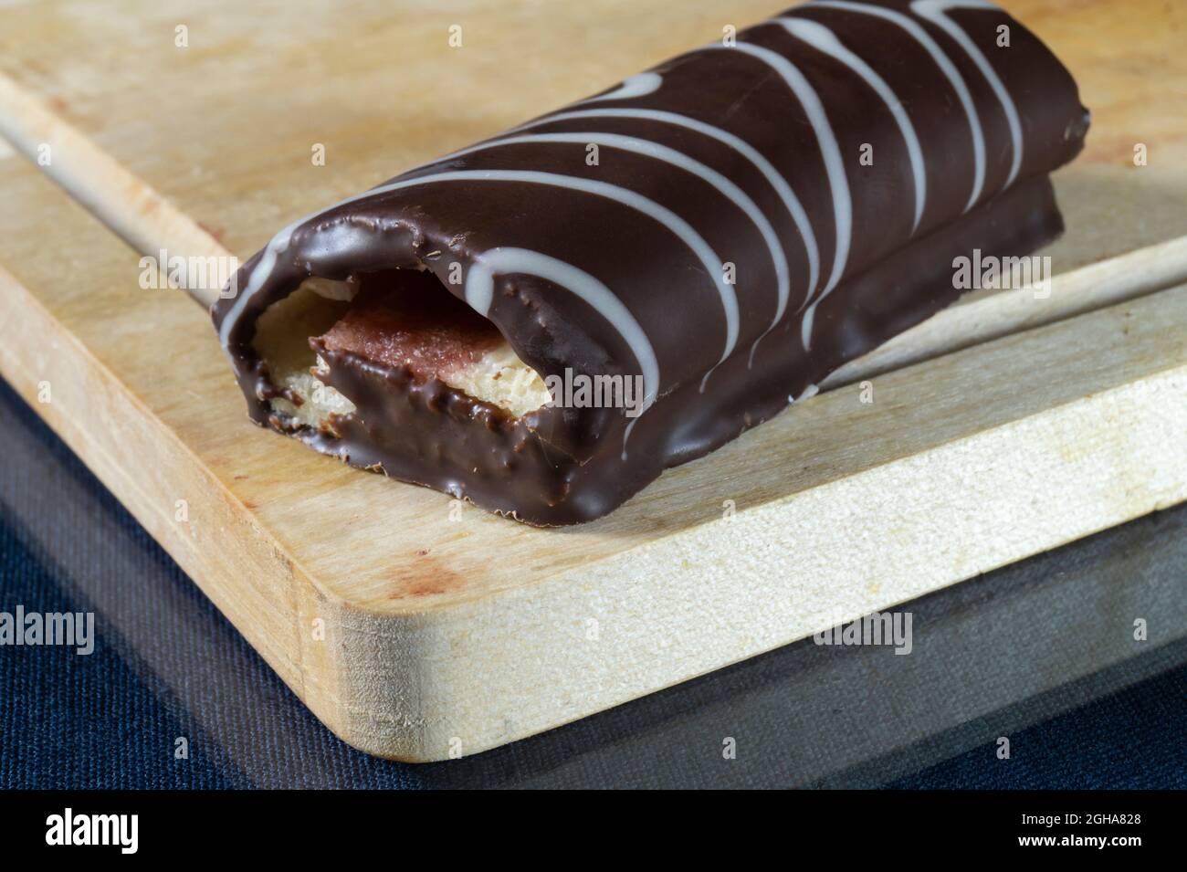 Süße Rolle auf einem Holzbrett in der Küche. Lebensmittel auf schwarzem Hintergrund Stockfoto