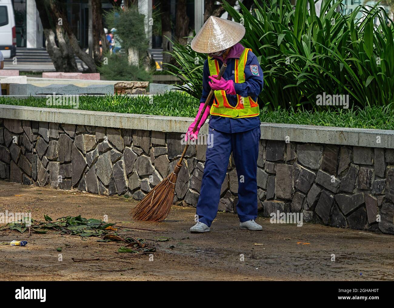 Stadtarbeiter fegen die Straße mit einem Besenstiel. Stadtstraße Hausmeister macht sanitäre Einrichtungen. Nha Trang, Vietnam: 2020-10-18. Stockfoto