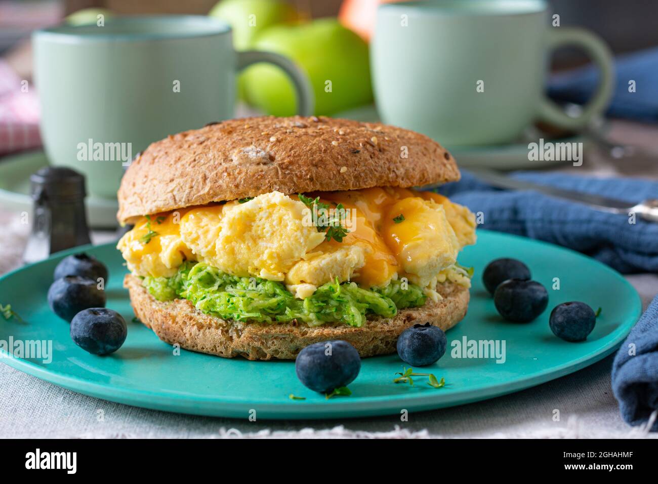 Frühstücksburger mit Rührei, Käse und Zucchini auf dem Küchentisch. Vorderansicht mit unscharfem Hintergrund Stockfoto