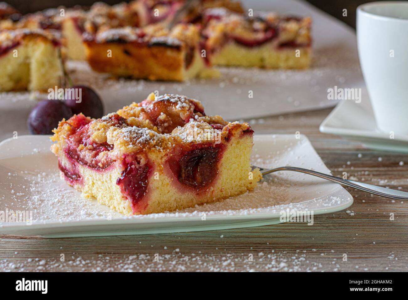 Pflaumenkuchen auf weißem Teller mit Gabel auf einem Kaffeetisch. Stockfoto