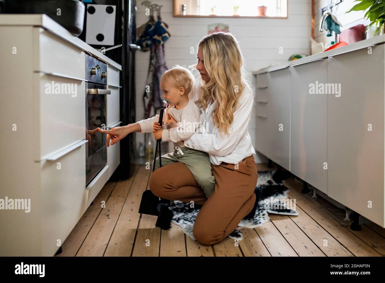 Frau zeigt dem Sohn in der Küche zu Hause einen Ofen Stockfoto