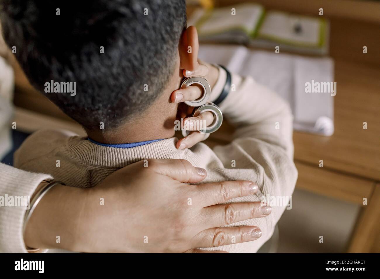 Zugeschnittene Hand der Mutter auf der Schulter des Sohnes zu Hause Stockfoto