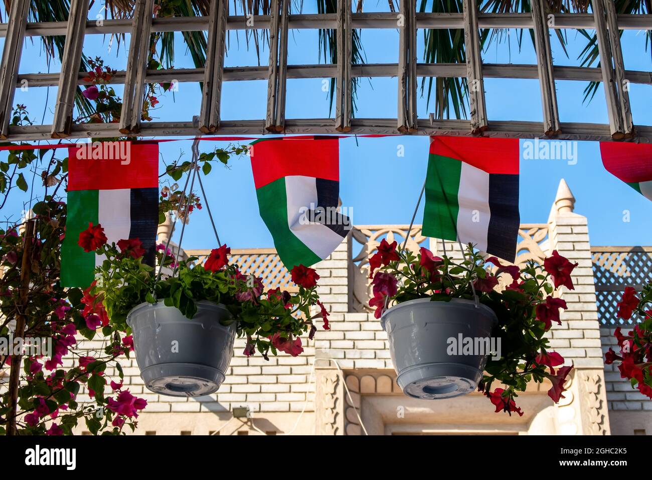 Die Nationalflaggendekorationen der Vereinigten Arabischen Emirate hängen zwischen Blumen, Nationalfeiertag der Vereinigten Arabischen Emirate, Dubai. Stockfoto