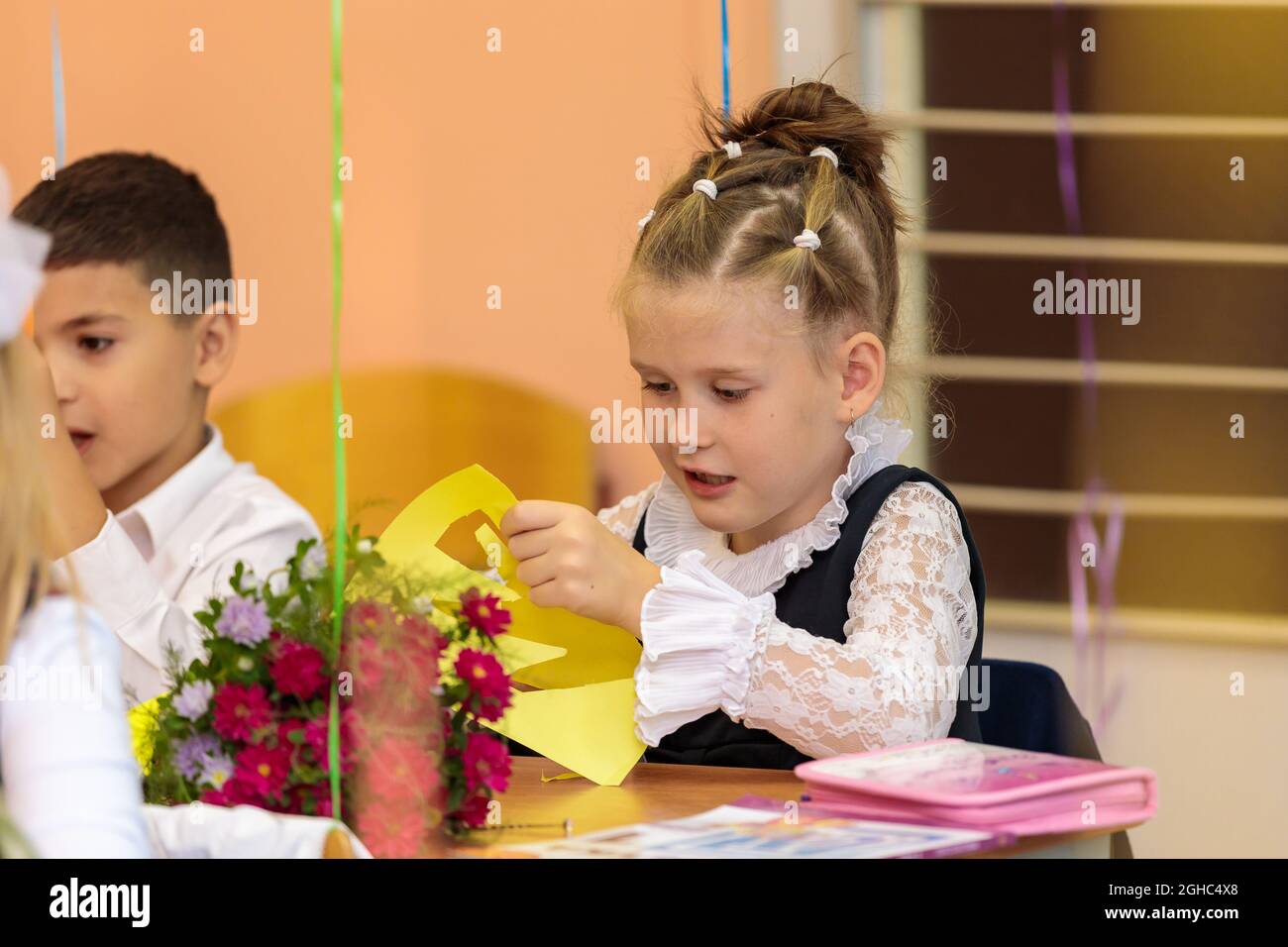 Erstklässler in der Lektion schneiden Zahlen für Anwendungen aus Papier aus. Schule, Wissenstag. Moskau, Russland, 1. September 2021 Stockfoto