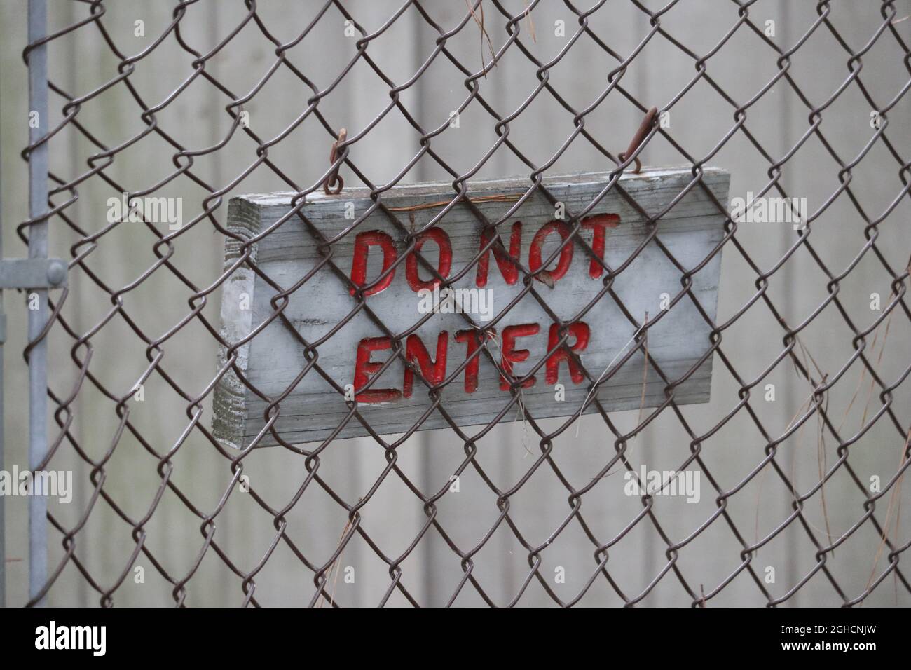 Ein „Do Not Enter“-Schild warnt Wanderer davor, sich außerhalb des von einem Kettengliederzaun umgebenen Bereichs aufzuhalten. Stockfoto