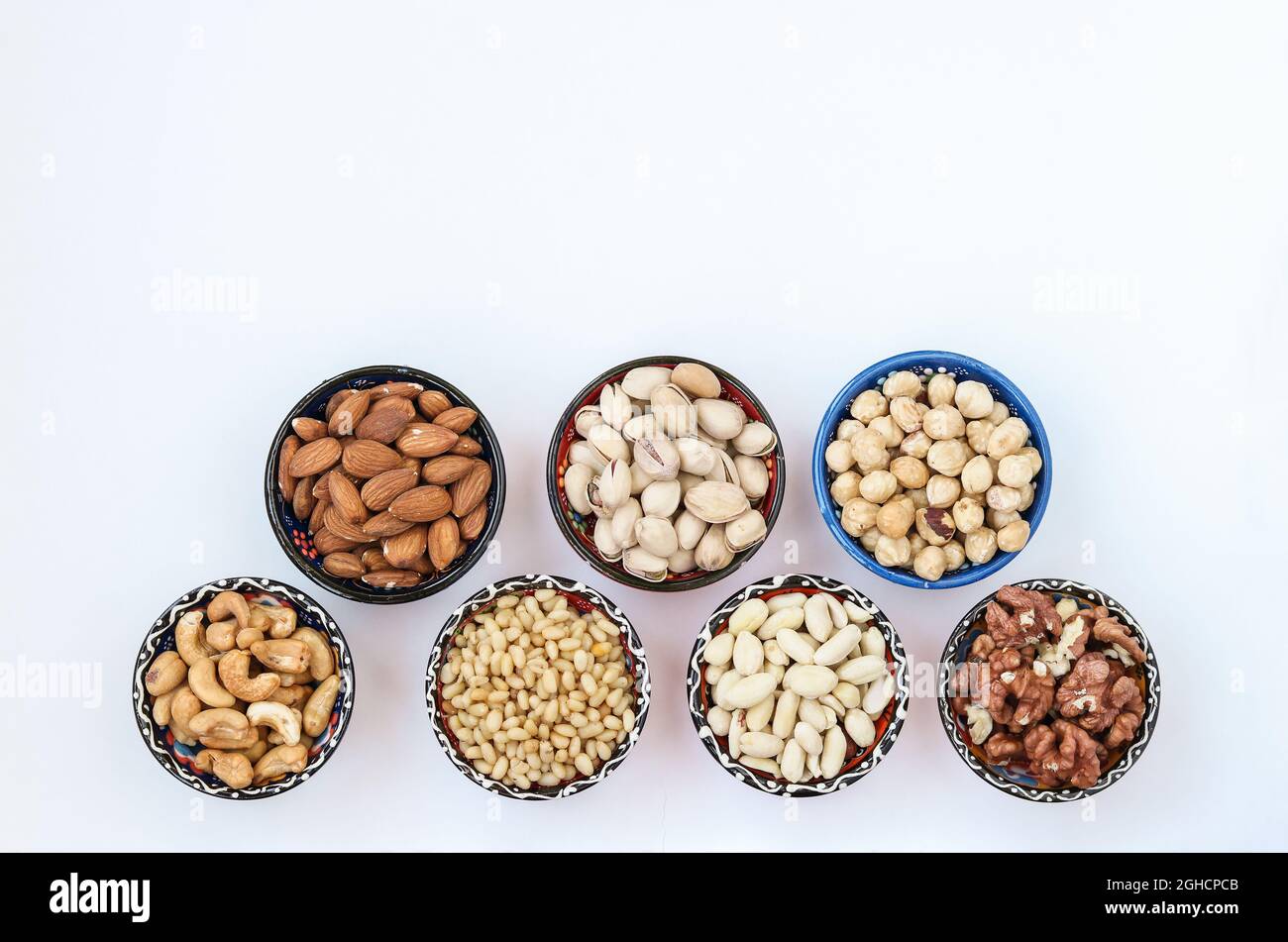 Verschiedene Arten von Nüssen: Erdnüsse, Pinienkerne, Cashewkerne, Mandeln, Haselnüsse, Walnüsse und Pistazien auf weißem Hintergrund. Draufsicht. Speicherplatz kopieren Stockfoto