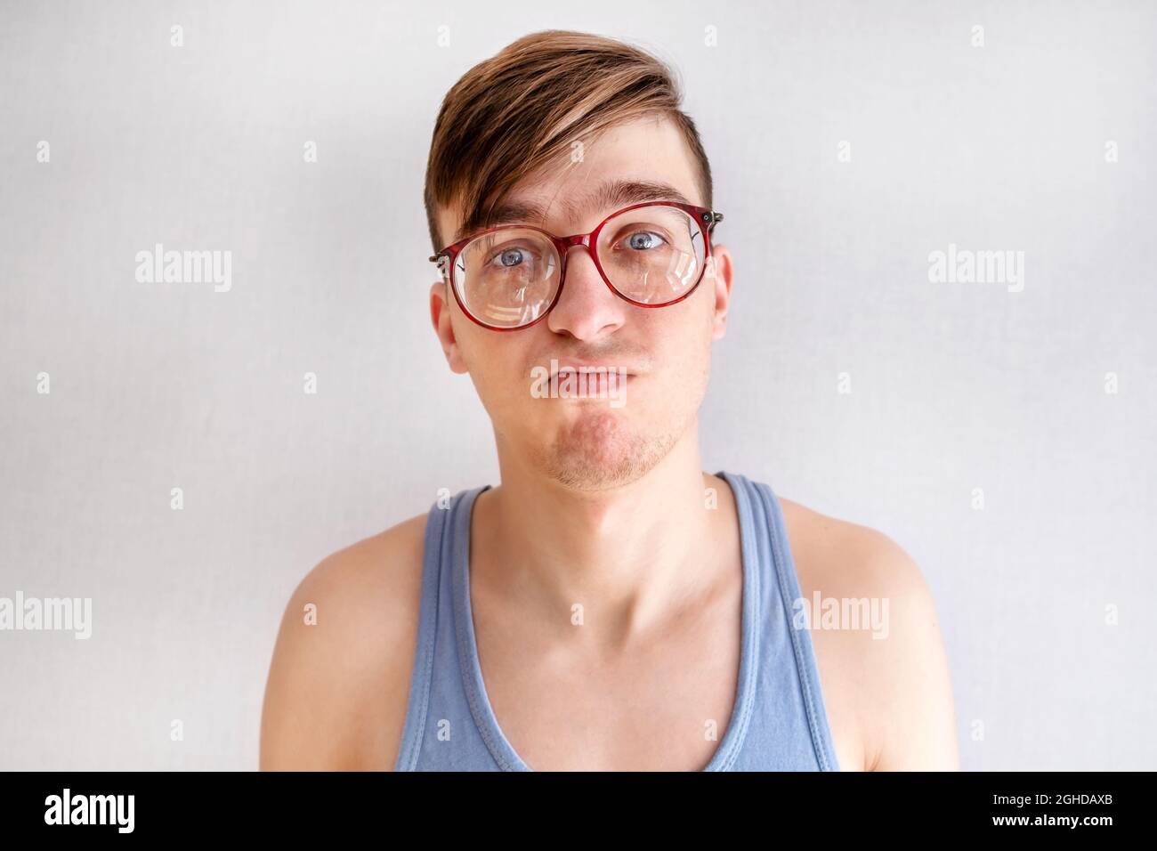 Trauriger junger Mann im Unterhemd an der weißen Wand Nahaufnahme Stockfoto