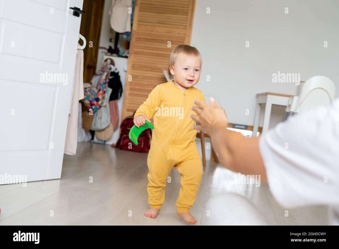 Blonde blauäugige Kind mit Kunststoff geometrische Spielzeug in der Hand gehen zu gesichtslosen Mutter Stockfoto