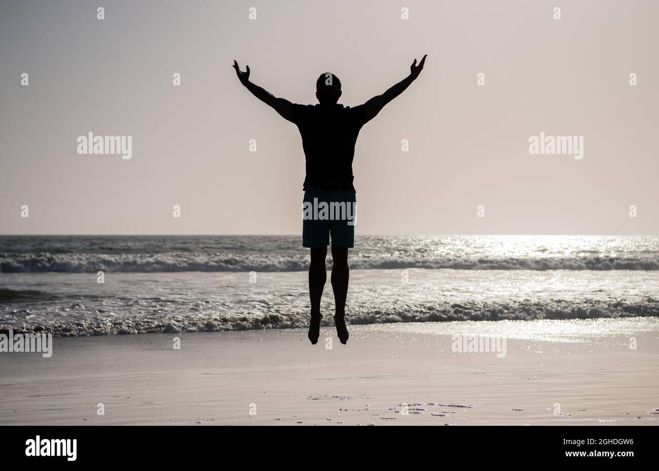 Fühlen Sie Freiheit. Jung und frei. Sportler springen im Meer. Morgendliche Workout-Aktivität. Stockfoto