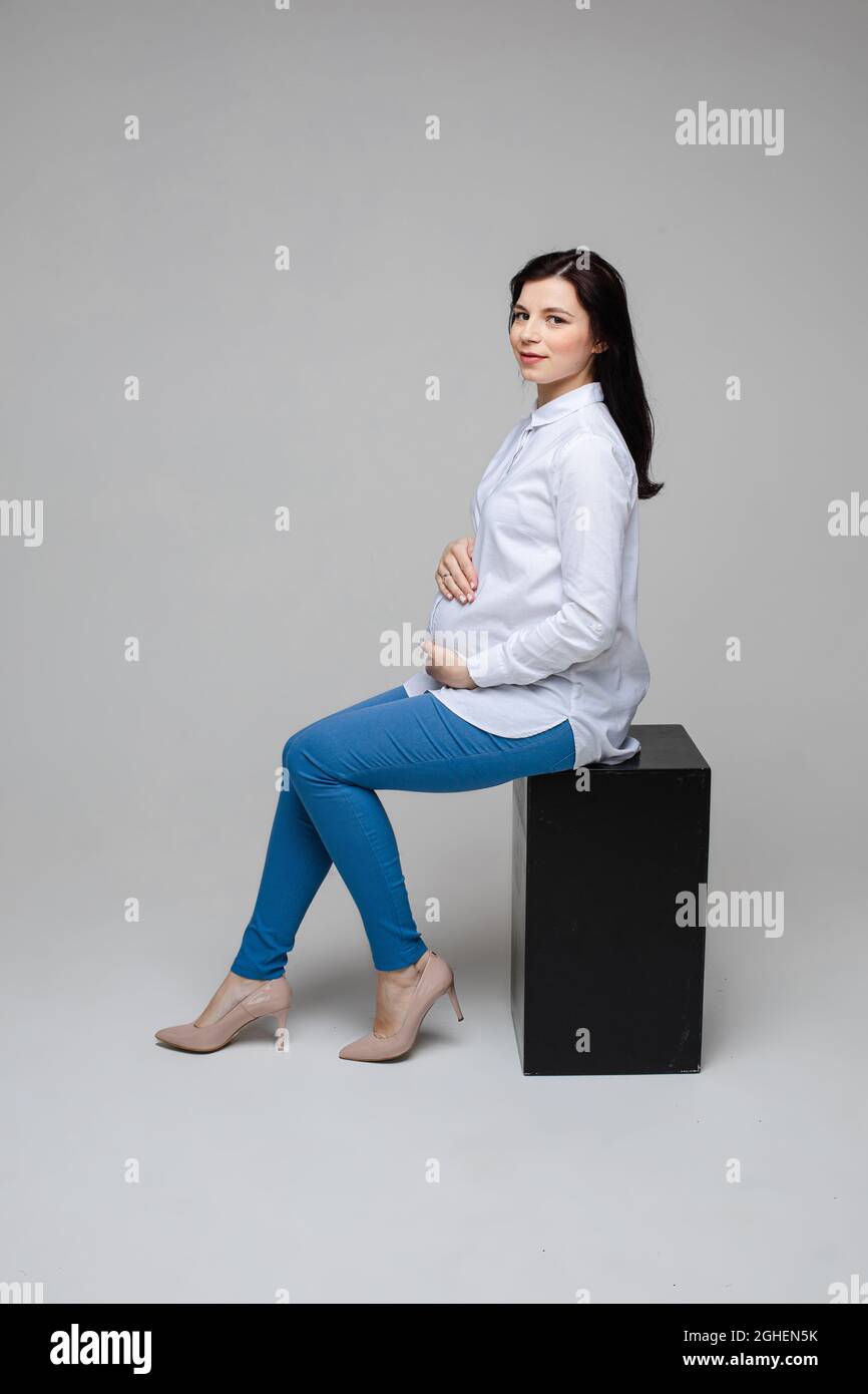 Schöne schwanger Büroangestellte in Absätzen umarmen Bauch. Stockfoto
