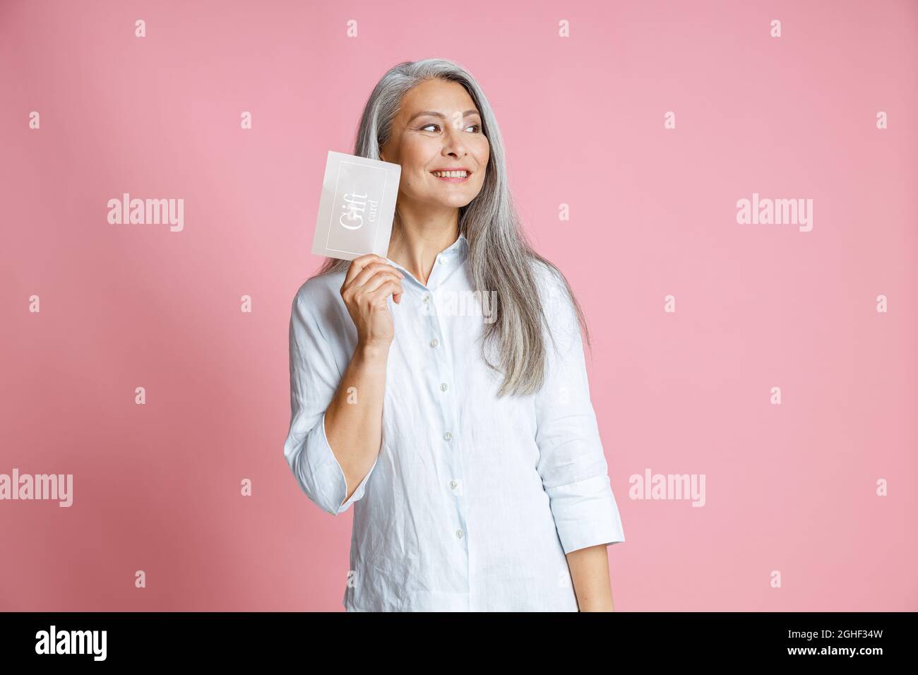 Hübsche silberhaarige asiatische Frau hält Geschenkkarte mit Ideen im Studio Stockfoto