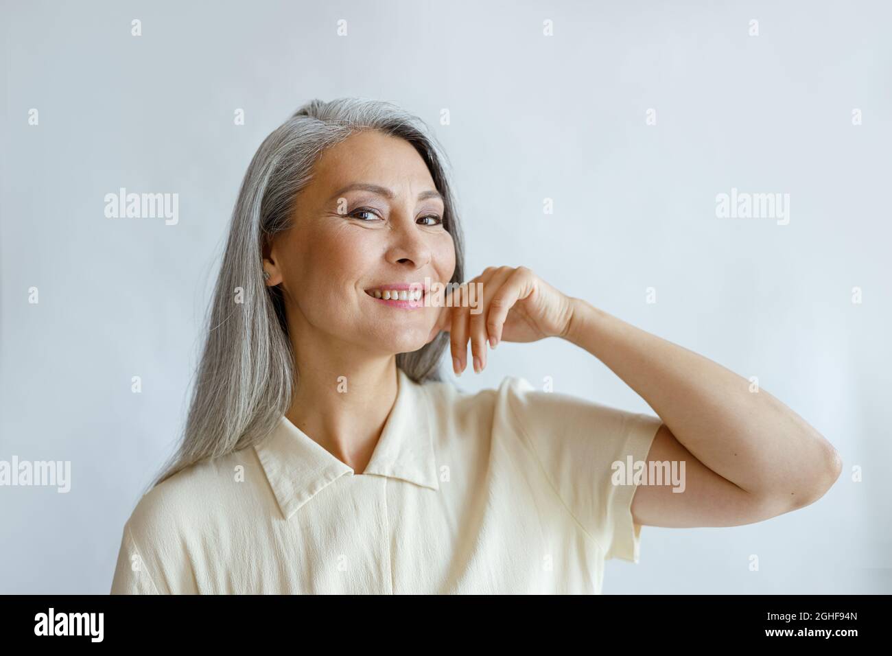 Elegante Frau mittleren Alters mit Hufhaar Posen auf hellem Hintergrund Stockfoto