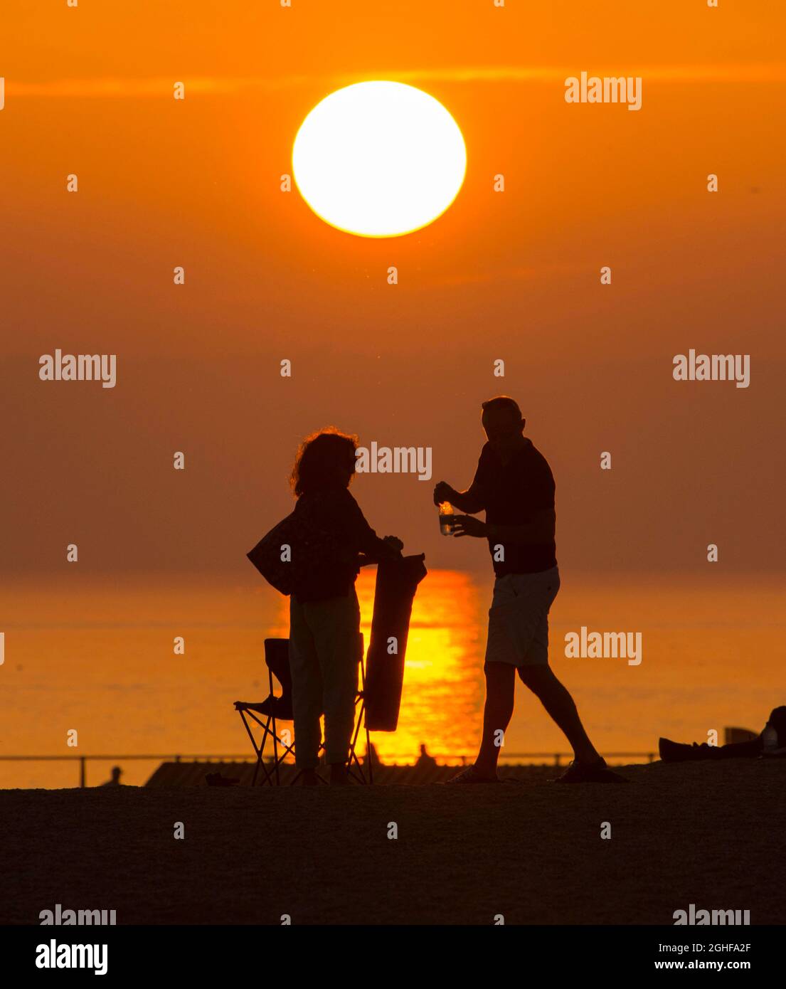 West Bay, Dorset, Großbritannien. September 2021. Wetter in Großbritannien. Die Strandbesucher werden im Badeort West Bay in Dorset nach einem Tag glühender, heißer Sonne während einer Mini-Hitzewelle vor einem goldorangen Sonnenuntergang geschildet. Bildnachweis: Graham Hunt/Alamy Live News Stockfoto