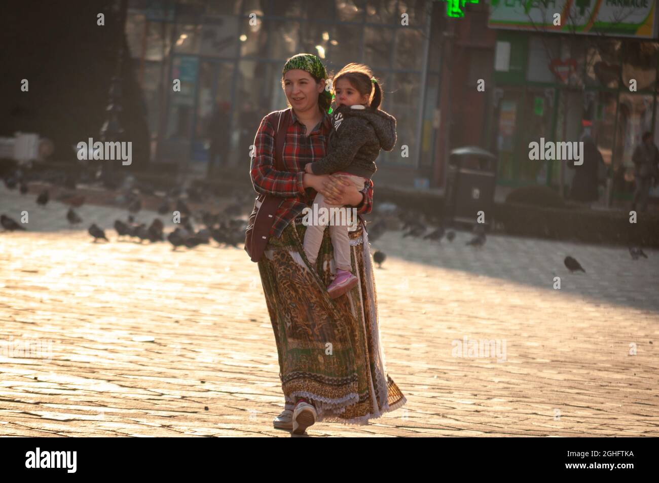 Timisoara, Rumänien - 05. September 2016: Zigeunerin, die mit dem Kind in den Armen auf der Straße unterwegs ist. Echte Menschen. Stockfoto