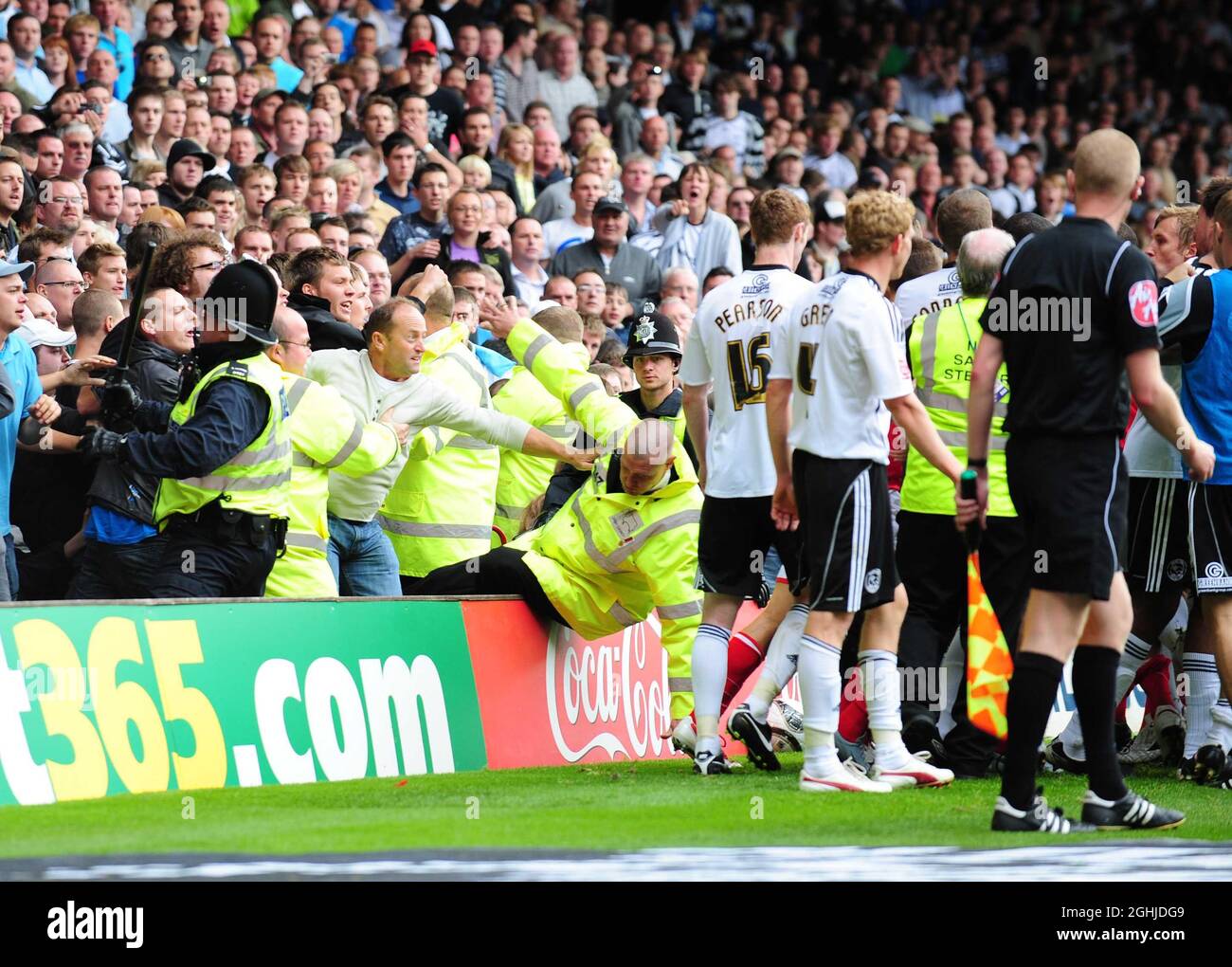 Ein Steward stürzt um sich und ein Polizist zieht seinen Batton (L), während die Derby-Fans am Ende des Spiels während des Coca-Cola-Meisterschaftsspiels auf dem City Ground, Nottingham, vor den anflatschenden Spielern aufsteigen. Stockfoto