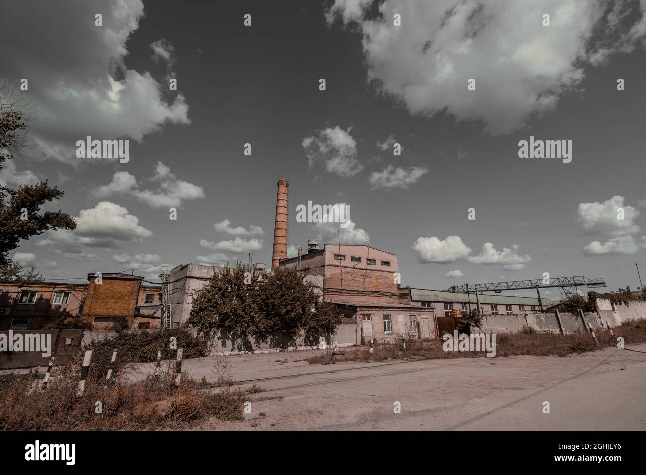 Düstere alte Ziegelfabrik mit einem Kamin gegen den grauen Himmel. Stockfoto